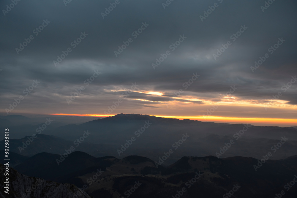 Mountain range with visible silhouettes through the morning colorful fog. Sunsire over the mountains.