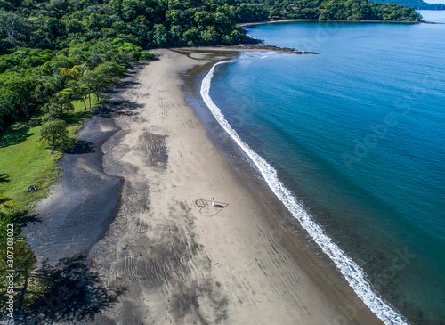 Aerial shot of wedding dress couple on the tropical beach Playa Arenillas in Costa Rica with a heart drawn into Sand