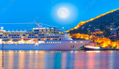 Beautiful white giant luxury cruise ship on stay at Alanya harbor with full moon"Elements of this image furnished by NASA"