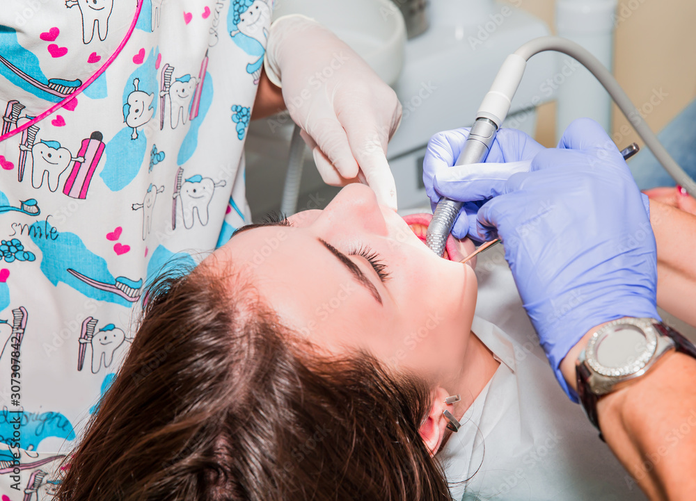 Dentist and his assistant carrying out a thorough examination (real treatment) Dentist and his assistant carrying out a thorough examination (real treatment)