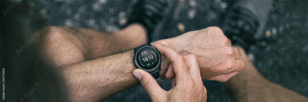 Foto Stock Smartwatch smart wearable tech gadget for fitness health active  lifestyle. Fit young man using new sports watch on jogging run checking his  heart rate banner panorama. | Adobe Stock