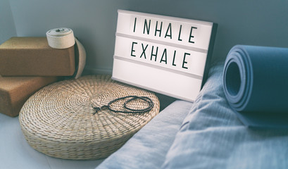 Fototapete Yogaschule Yoga-Atmung INHALE EXHALE-Zeichen im Fitnesskurs auf einer inspirierenden Nachricht des Leuchtkastens mit Trainingsmatte, Mala-Perlen, Meditationskissen. Accessoires für einen fitten Lebensstil zu Hause.  © Maridav