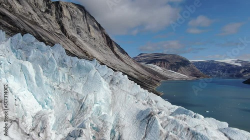Slow aerial drone ride over the glacier of Sam Ford Fjord, Canada, near Greenland, revealing high details of natural ice and rocks with harsh and strange relief, on a sunny day