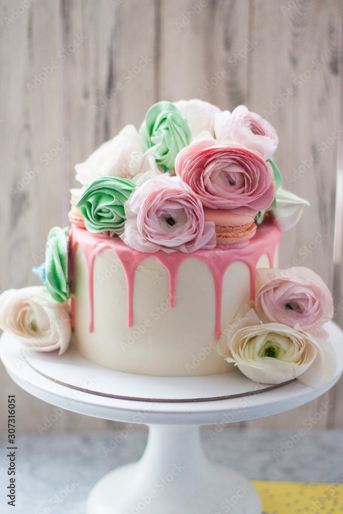 White cake with pink melted chocolate decorated with fresh flowers, roses, ranunculuses, macaroons and meringue swirls. White cake with pink melted chocolate decorated with fresh flowers, roses, ranunculuses, macaroons and meringue swirls.