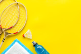 Tennis equipment - rockets, shuttlecock - on yellow background top-down frame copy space
