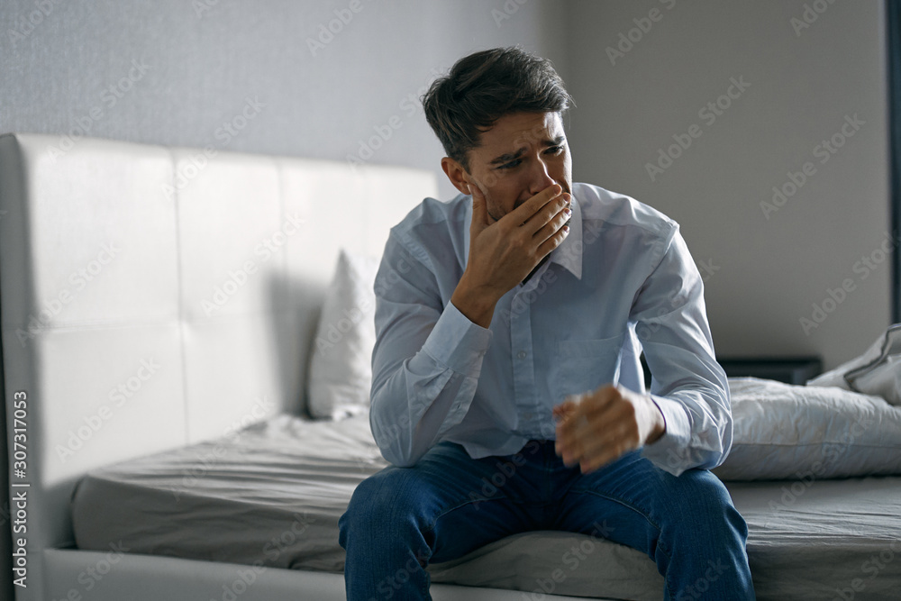 Fototapeta premium young man sitting on sofa and talking on cell phone