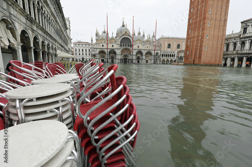 red chairs of a sidewalk cafe in Saint Mark Square in Venice wit