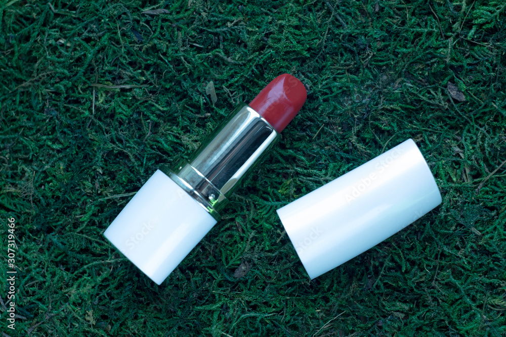 Red lipstick in a white lies on the moss, top view. Bright dark red lipstick on lush green moss Stock Photo | Adobe Stock