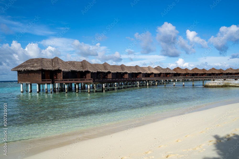 Beautiful over the water bungalow beach villas in the Maldives on the Indian Ocean on a sunny day