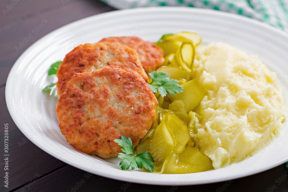 Homemade fried cutlets/meatballs with mashed potatoes and pickled cucumber on white plate. Homemade fried cutlets/meatballs with mashed potatoes and pickled cucumber on white plate.