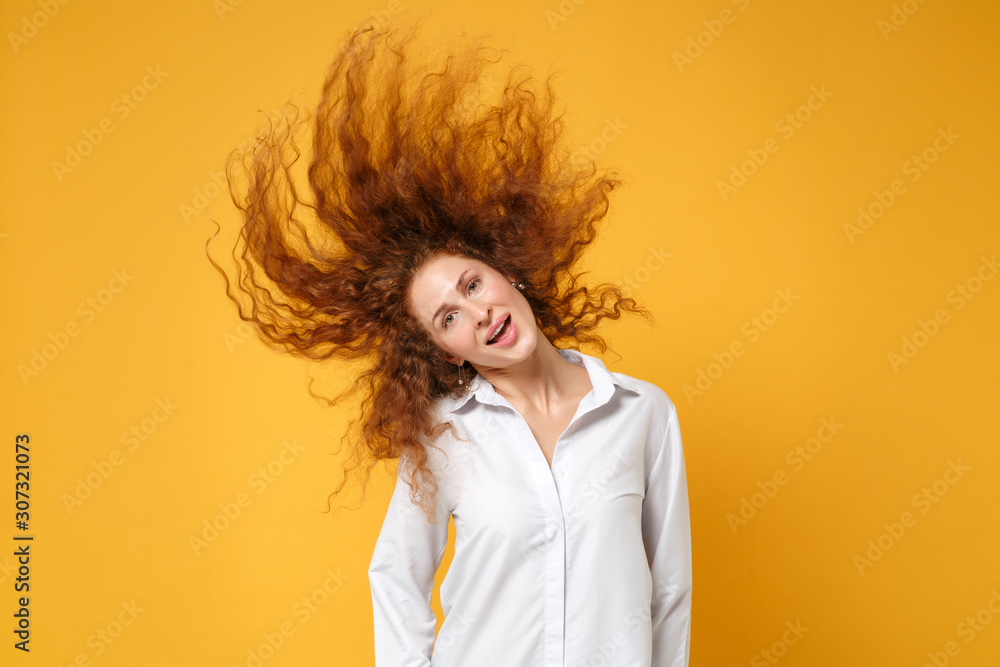 Beautiful young redhead woman girl in white shirt posing isolated on yellow orange wall background. People lifestyle concept. Mock up copy space. Having fun, fooling around, jump with fluttering hair. Beautiful young redhead woman girl in white shirt posing isolated on yellow orange wall background. People lifestyle concept. Mock up copy space. Having fun, fooling around, jump with fluttering hair.