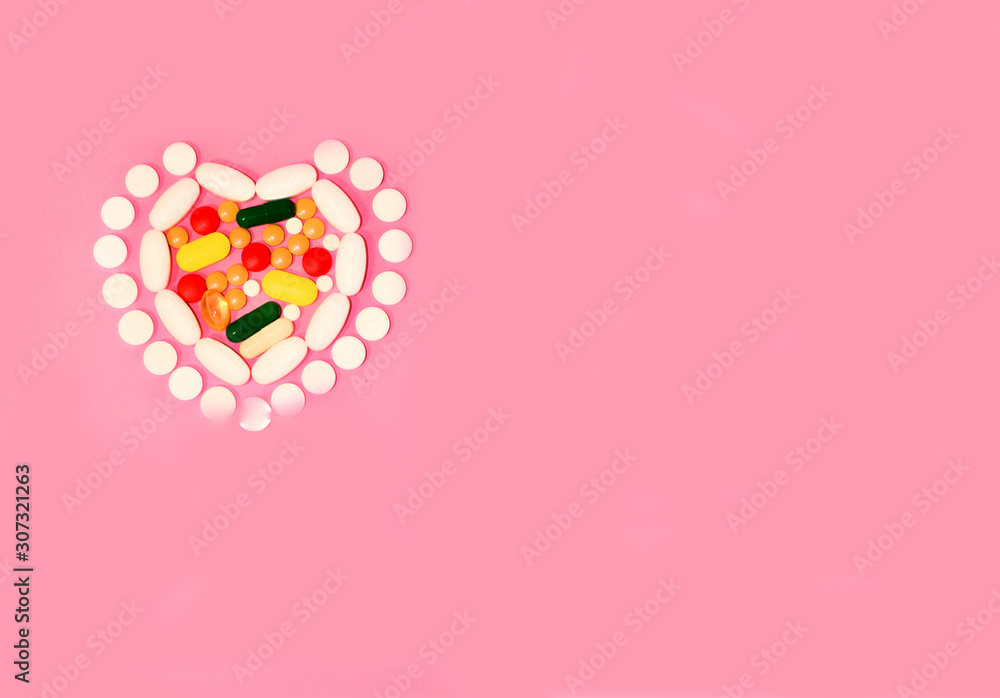 The pills are laid out in the shape of a heart. On a pink background. Top view. Space for text. The pills are laid out in the shape of a heart. On a pink background. Top view. Space for text.
