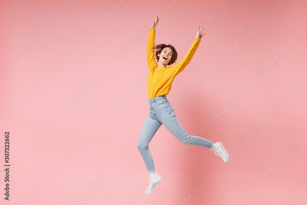 Cheerful young brunette woman girl in yellow sweater posing isolated on pastel pink background in studio. People lifestyle concept. Mock up copy space. Having fun fooling around rising hands, jumping. Cheerful young brunette woman girl in yellow sweater posing isolated on pastel pink background in studio. People lifestyle concept. Mock up copy space. Having fun fooling around rising hands, jumping.