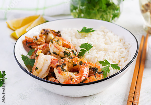 Grilled shrimps and boiled rice. King prawn tails in orange-garlic sauce with parsley.