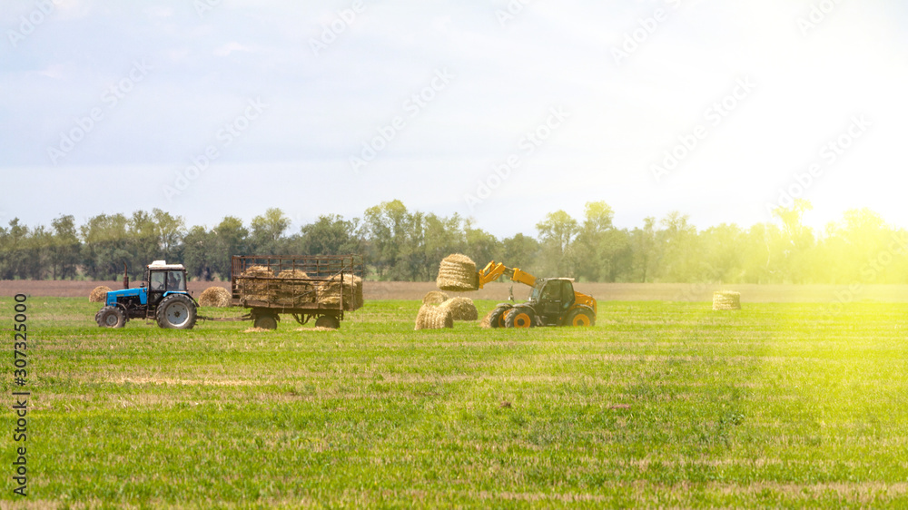Tractor loading hay bales on truck agricultural works
