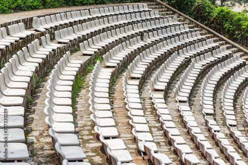 Rows of empty plastic chairs at old outdoor stadium © Quang