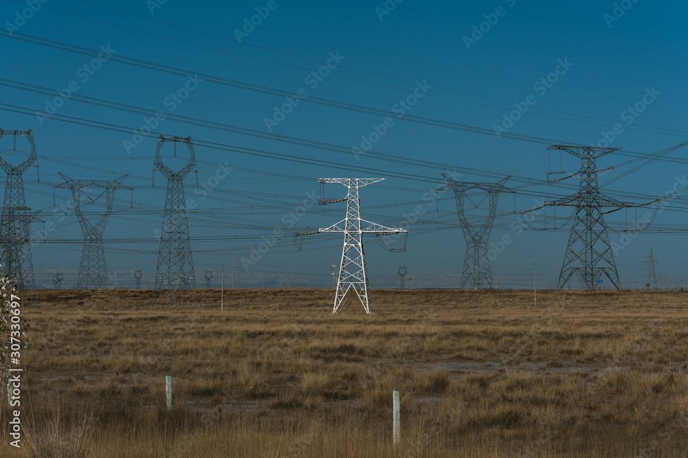 High voltage pylons on dry grassland