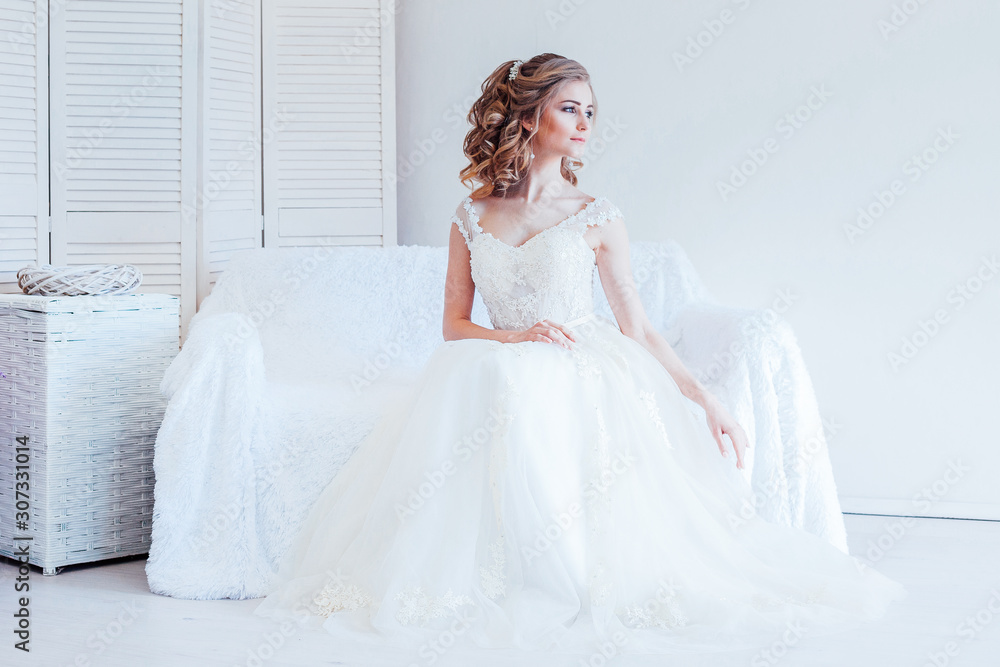 beautiful bride sitting on a white couch in wedding dress beautiful bride sitting on a white couch in wedding dress
