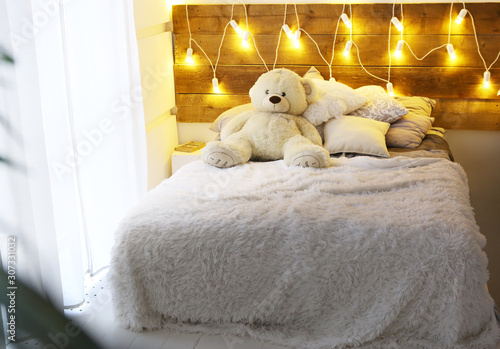 white bed with teddy bear with christmas garland light decoration photo