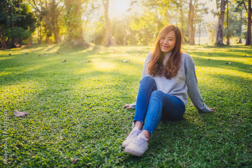 Portrait image of a beautiful asian woman sitting among nature in the park before sunset Portrait image of a beautiful asian woman sitting among nature in the park before sunset