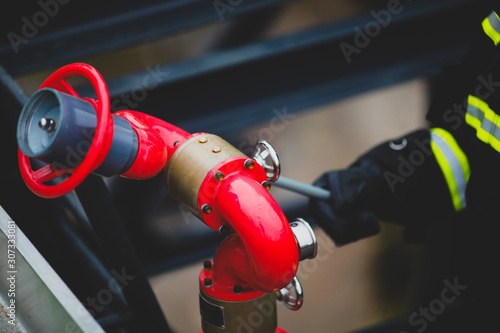 Details with the hands of a firefighter holding a fire suppression system (hydrant) on a hospital helipad. photo