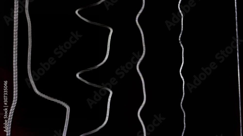Acoustic guitar strings vibrating while playing music creating amazing patterns and soundwaves while strumming chords and single notes heavily on black background of the soundhole close up detail shot