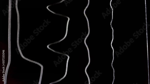 Acoustic guitar strings vibrating while playing music creating amazing patterns and soundwaves while strumming chords and single notes heavily on black background of the soundhole close up detail shot photo