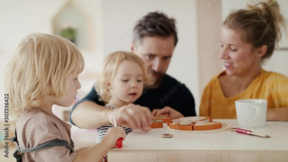 Young family with two small children indoors in bedroom playing with toys. Young family with two small children indoors in bedroom playing with toys.
