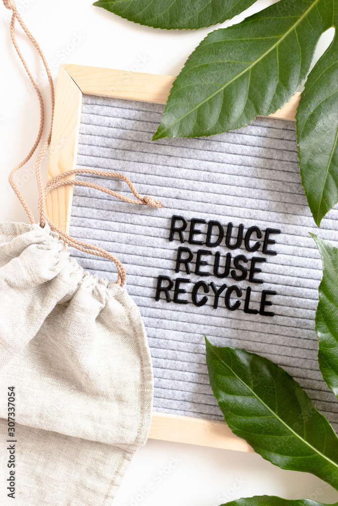 Green leaves, canvas bag and letterboard with quote Reduce Reuse ...