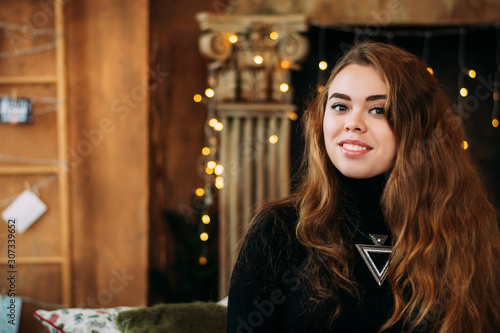 Portrait of girl on fireplace background with garlands. bokeh. Christmas studio photo.