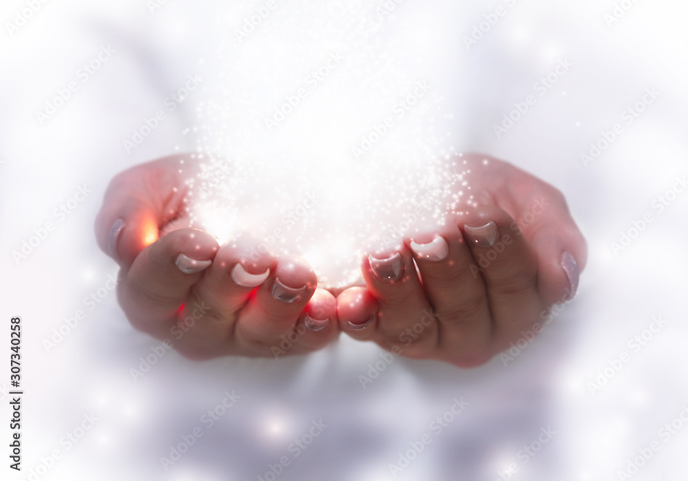 The magical effect emanating from female hands. Magic particles, light stream on an abstract background.
