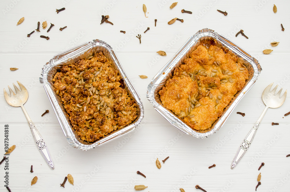 Indian food, fruit pies, subhadra and mithai, in foil plates on a white background, sprinkled with seeds, spices with two forks Indian food, fruit pies, subhadra and mithai, in foil plates on a white background, sprinkled with seeds, spices with two forks