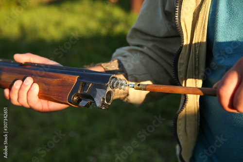 hunter's hands clean the rifle with a ramrod