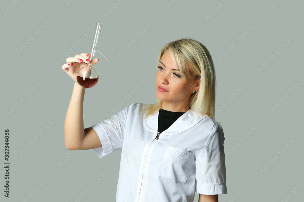 female lab technician in a white coat holding a flask with a reagent female lab technician in a white coat holding a flask with a reagent