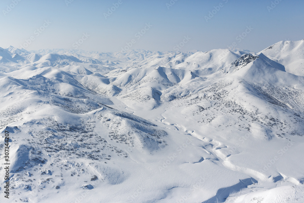 Top view of a snowy valley, mountains and hills. Beautiful aerial landscape. Traveling and hiking in the far north of Russia. Location place: Meingypilgyn Range, Chukotka, Siberia, Russian Far East.