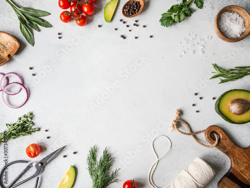 Fresh raw greens, vegetables, spices and kitchenwere frame on grey background. top view,
