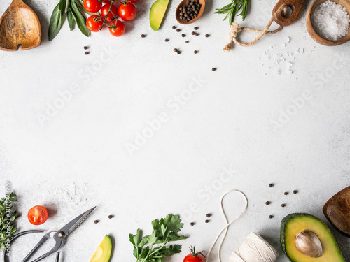 Fresh raw greens, vegetables, spices and kitchenwere frame on grey background. top view, photo