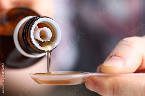 Sick man holding in hands vial with syrup close-up photo
