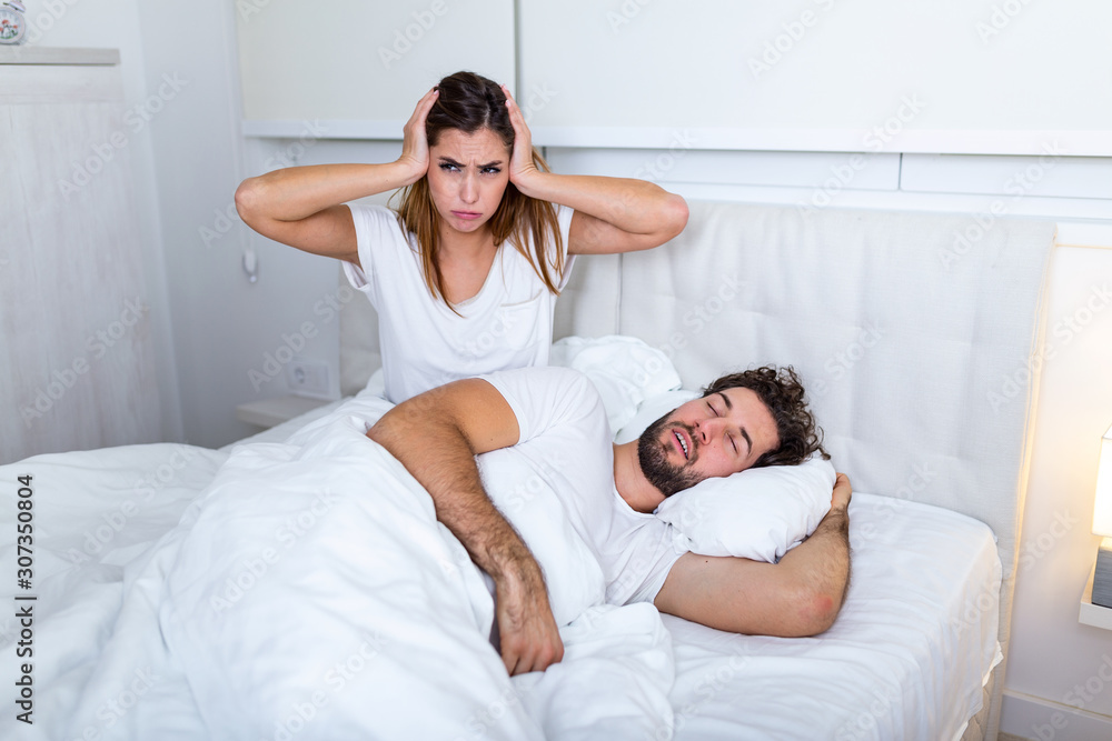 Snoring man. Couple in bed, man snoring and woman can not sleep. Picture of angry woman in bed with snoring man. Portrait of woman blocking ears with hands while man snoring on bed Snoring man. Couple in bed, man snoring and woman can not sleep. Picture of angry woman in bed with snoring man. Portrait of woman blocking ears with hands while man snoring on bed