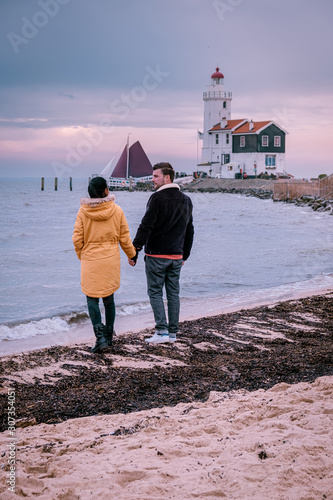 couple watching sunset by Marken lighthouse a small fishing village near Amsterdam Netherlands photo