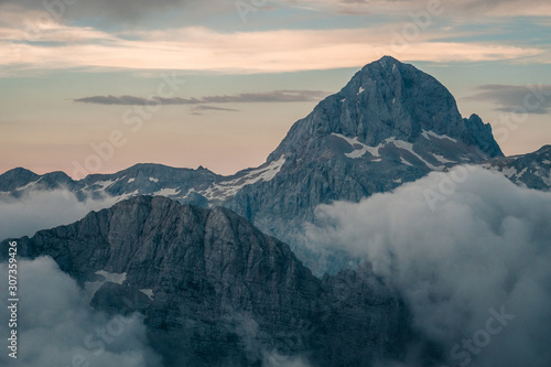 Sunset view on Triglav summit in clouds, in Julian Alps, Slovenia after hike on Jubilee via ferrata, hut Koča na Kredarici visible