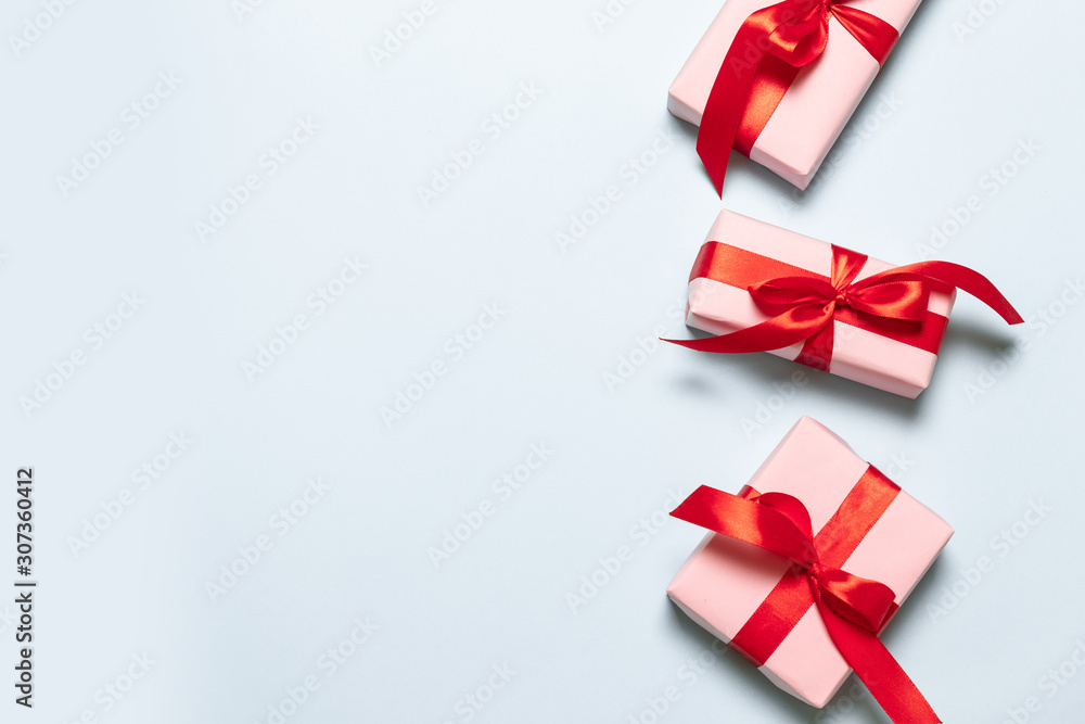 Flat lay composition with pink boxes with red satin ribbons on a blue background for birthday, mother day, merry christmas and new year Flat lay composition with pink boxes with red satin ribbons on a blue background for birthday, mother day, merry christmas and new year