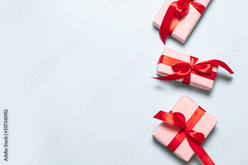 Flat lay composition with pink boxes with red satin ribbons on a blue background for birthday, mother day, merry christmas and new year