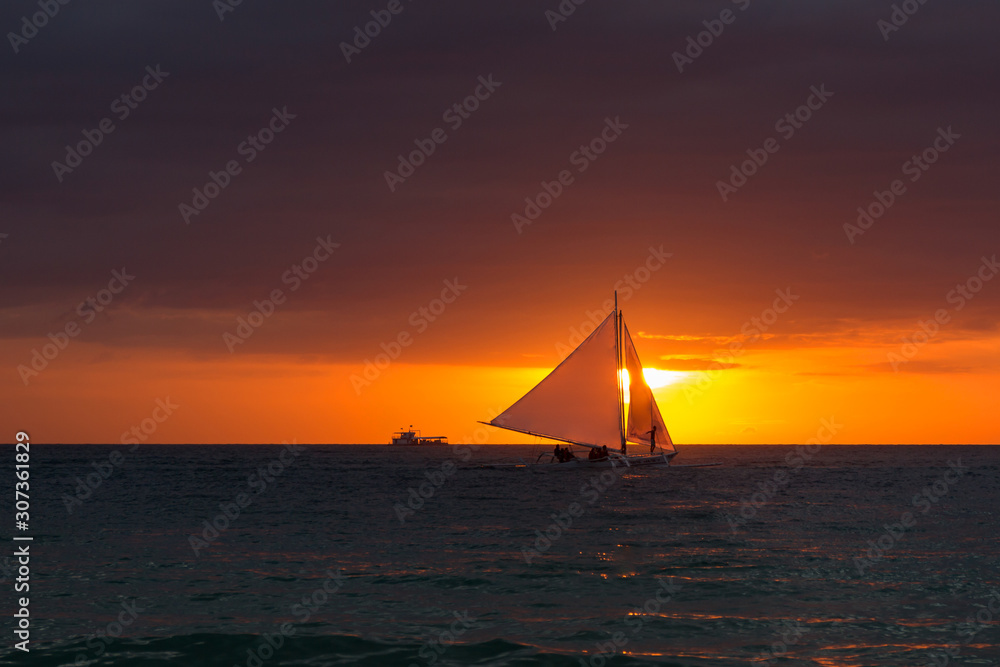 Beautiful sunset. The ship sails the waves during sunset. Sea walk on a sea ship. Silhouette of the ship at sunset.