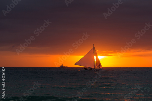 Beautiful sunset. The ship sails the waves during sunset. Sea walk on a sea ship. Silhouette of the ship at sunset. © liiset
