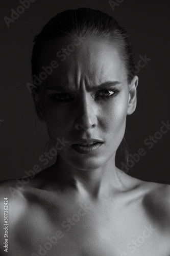 Black-white portrait of a girl close-up. Female emotions of disgust and discontent on her face.