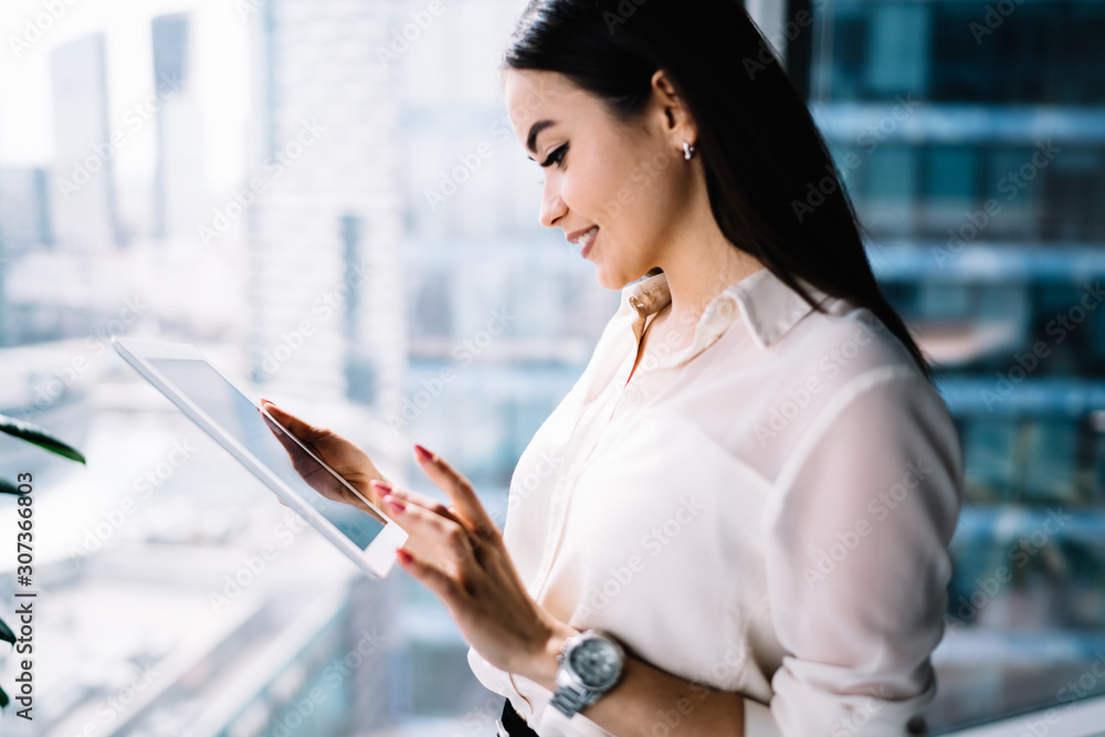 Smiling female browsing tablet at workplace Smiling female browsing tablet at workplace