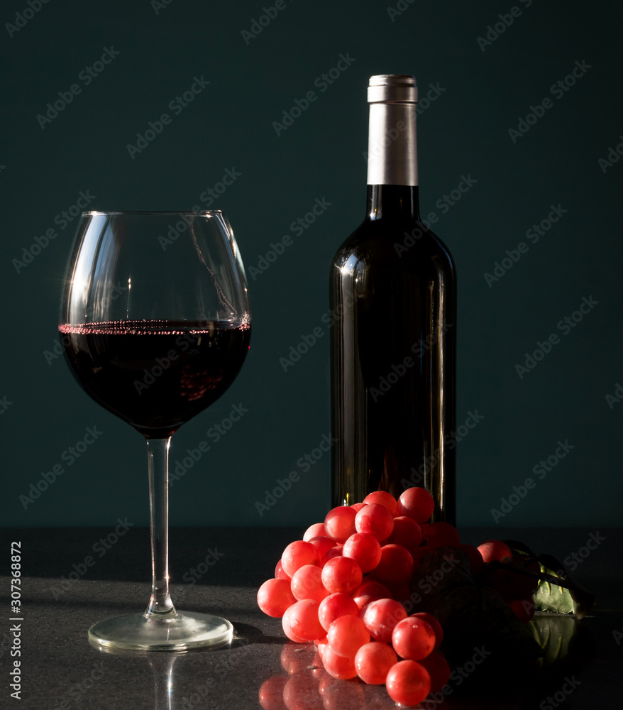 Red wine in a glass with grape cane on the table.