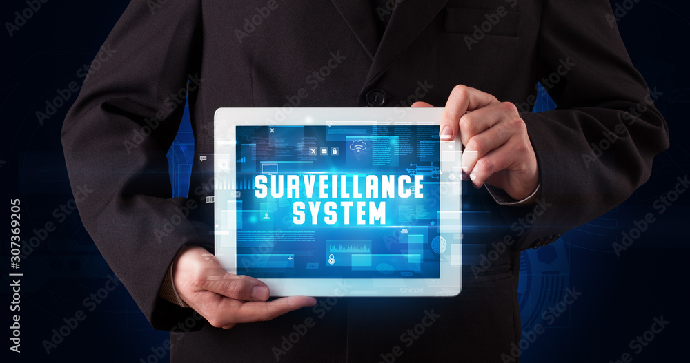 Young business person working on tablet and shows the digital sign: SURVEILLANCE SYSTEM Young business person working on tablet and shows the digital sign: SURVEILLANCE SYSTEM