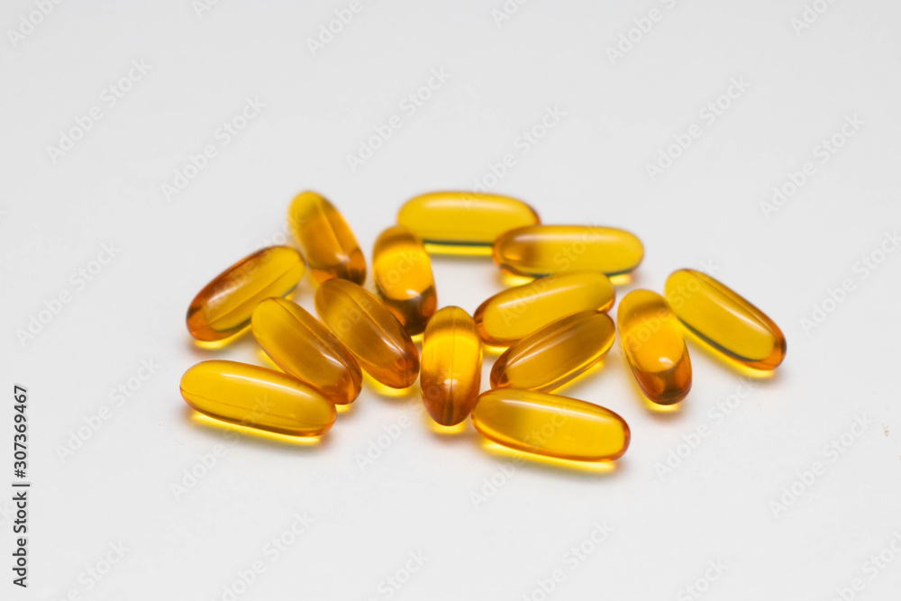 Capsules with fish oil on a white background, top view. The use of vitamin D, omega-3. Capsules with fish oil on a white background, top view. The use of vitamin D, omega-3.